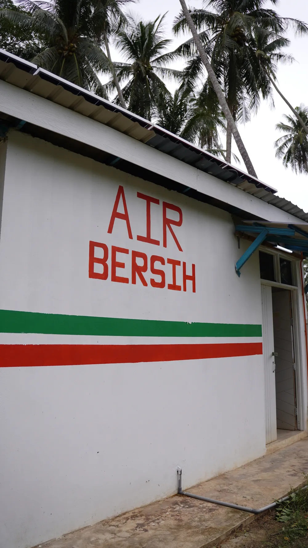 Air Bersih (clean water) signage painted on the exterior wall of the pump house