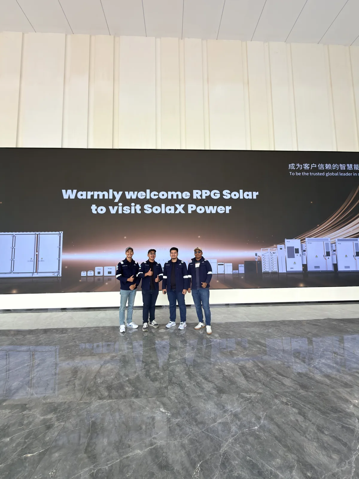 SolaX Power welcome screen reading 'Warmly welcome RPG Solar to visit SolaX Power', with the RPG Solar team posing in front of it