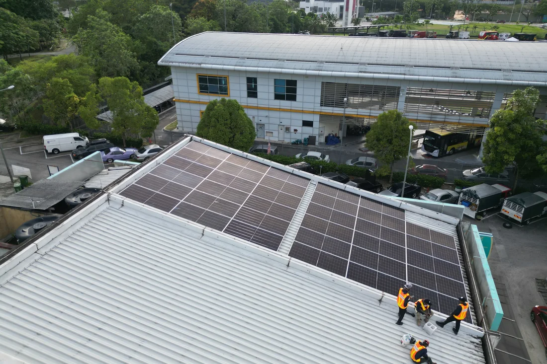 Aerial view of solar panels installed on the rooftop of a commercial depot building, with vehicles parked below