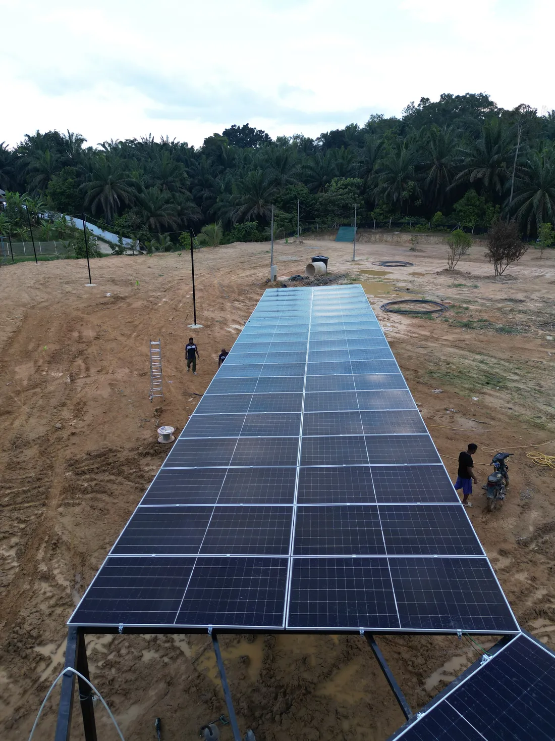 Aerial view of a triangular ground-mount solar panel array on cleared land