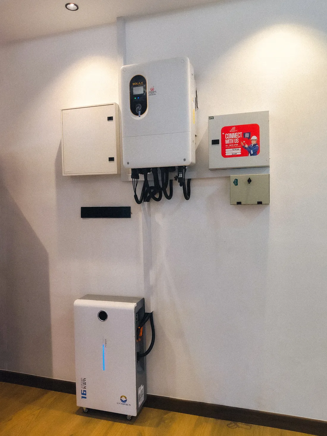 Close-up of a completed hybrid inverter and battery installation mounted on an interior wall