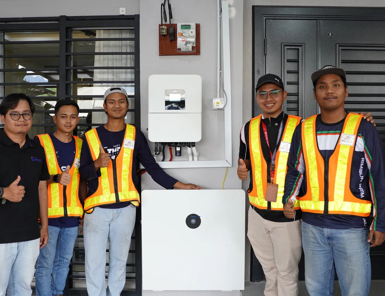 The RPG install team with a customer, standing beside a freshly installed hybrid inverter and battery